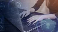 Eine Person schreibt an einem Laptop mit Bildelementen zur Datensicherheit.