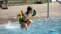 Junge mit Schwimmflügeln springt ins Wasser