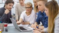 Gruppe junger Menschen um einen Laptop